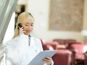 Happy female doctor talking to a patient on a phone in clinic